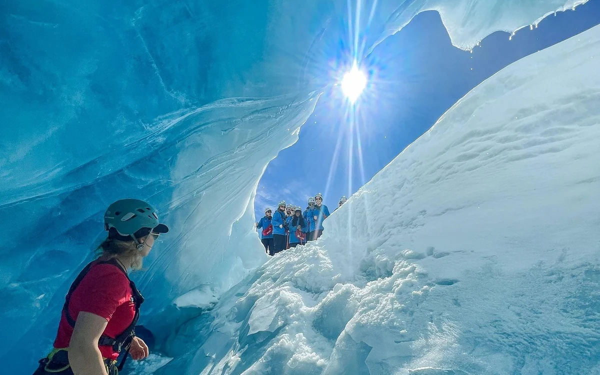 A line of hikers in crampons crossing the ice on Franz Josef Glacier